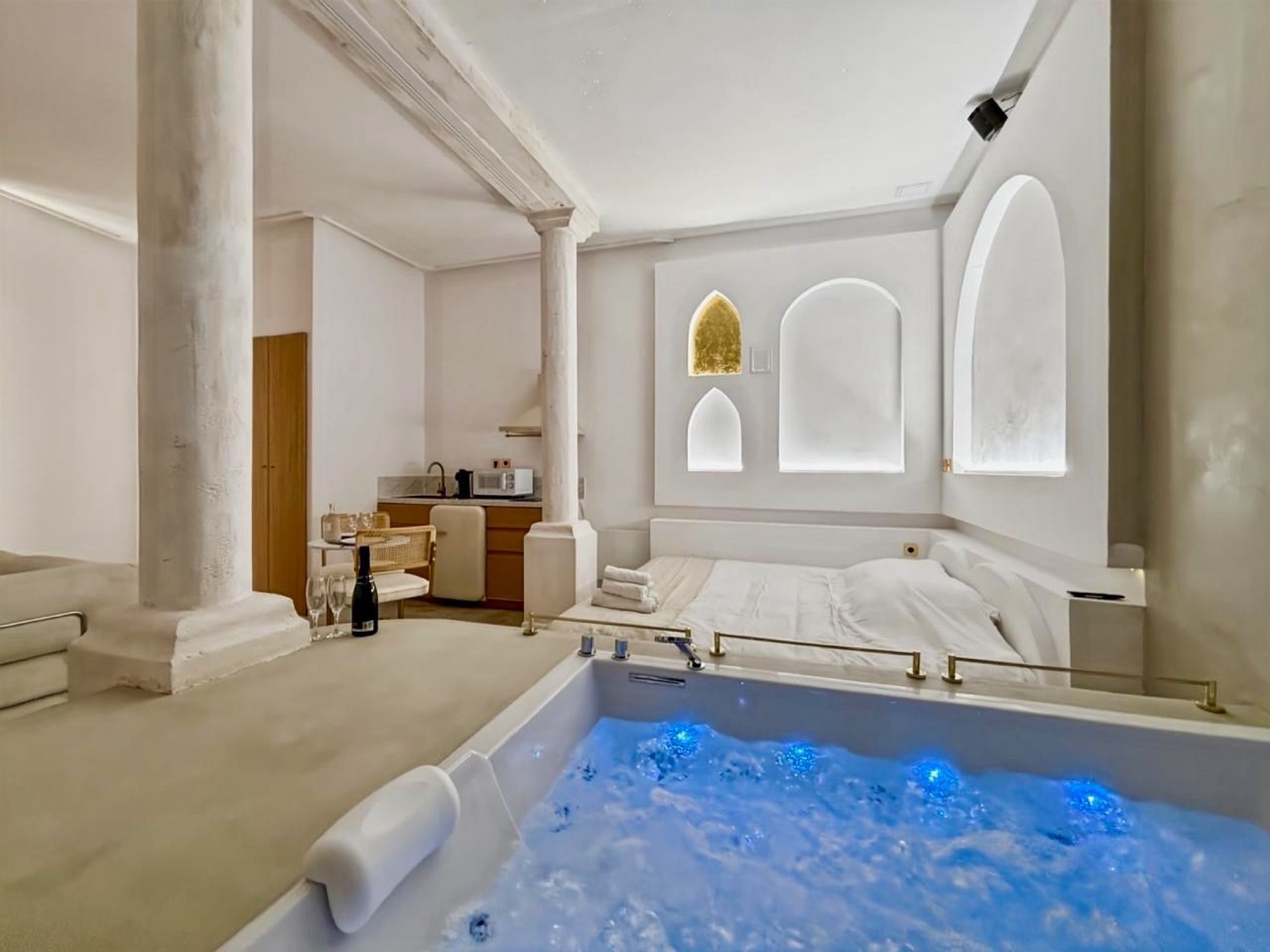 Balnéo suite with blue-lit jacuzzi and kitchen corner