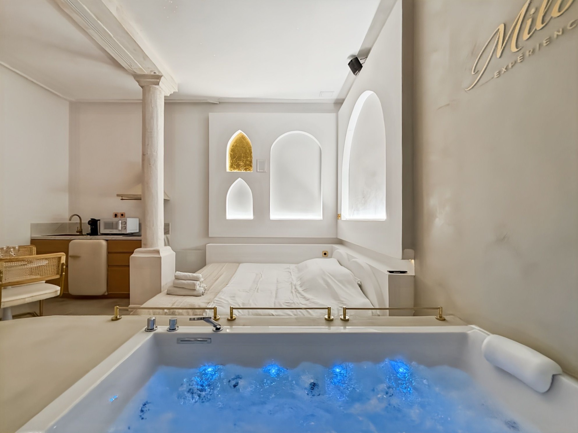 Blue-lit jacuzzi facing the bed in the Balnéo Room
